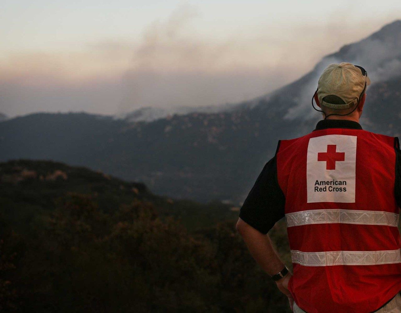 Man looking at mountains wearing red cross vest